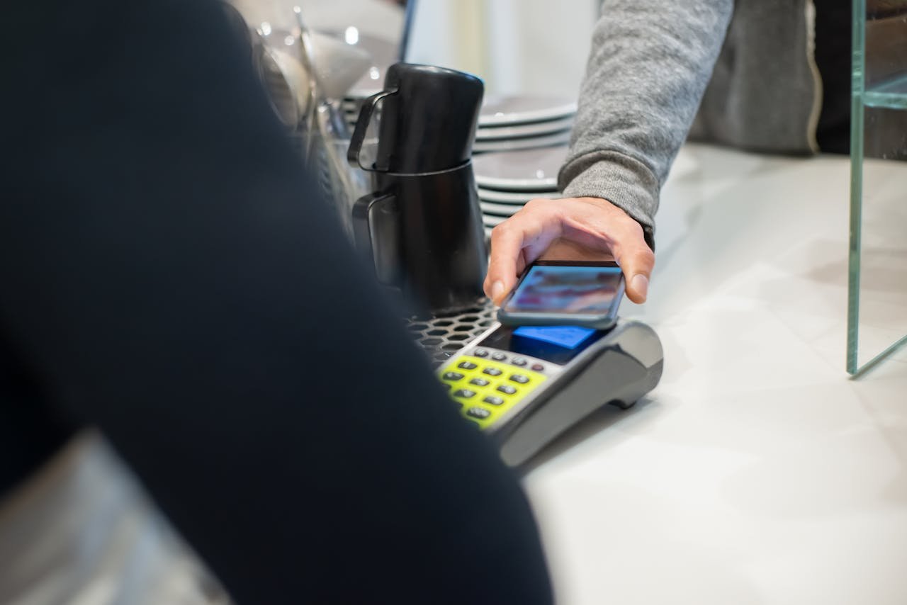 A customer makes a contactless payment using a smartphone at a café, showcasing modern digital transactions.